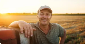 Man in field leaning on equipment